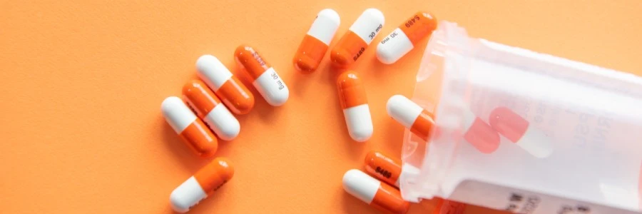 Prescription drugs on an orange background with a pill bottle